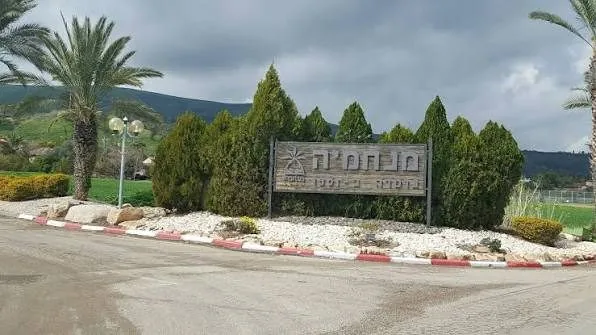 שלט הכניסה למנחמיה על רקע הגבעות